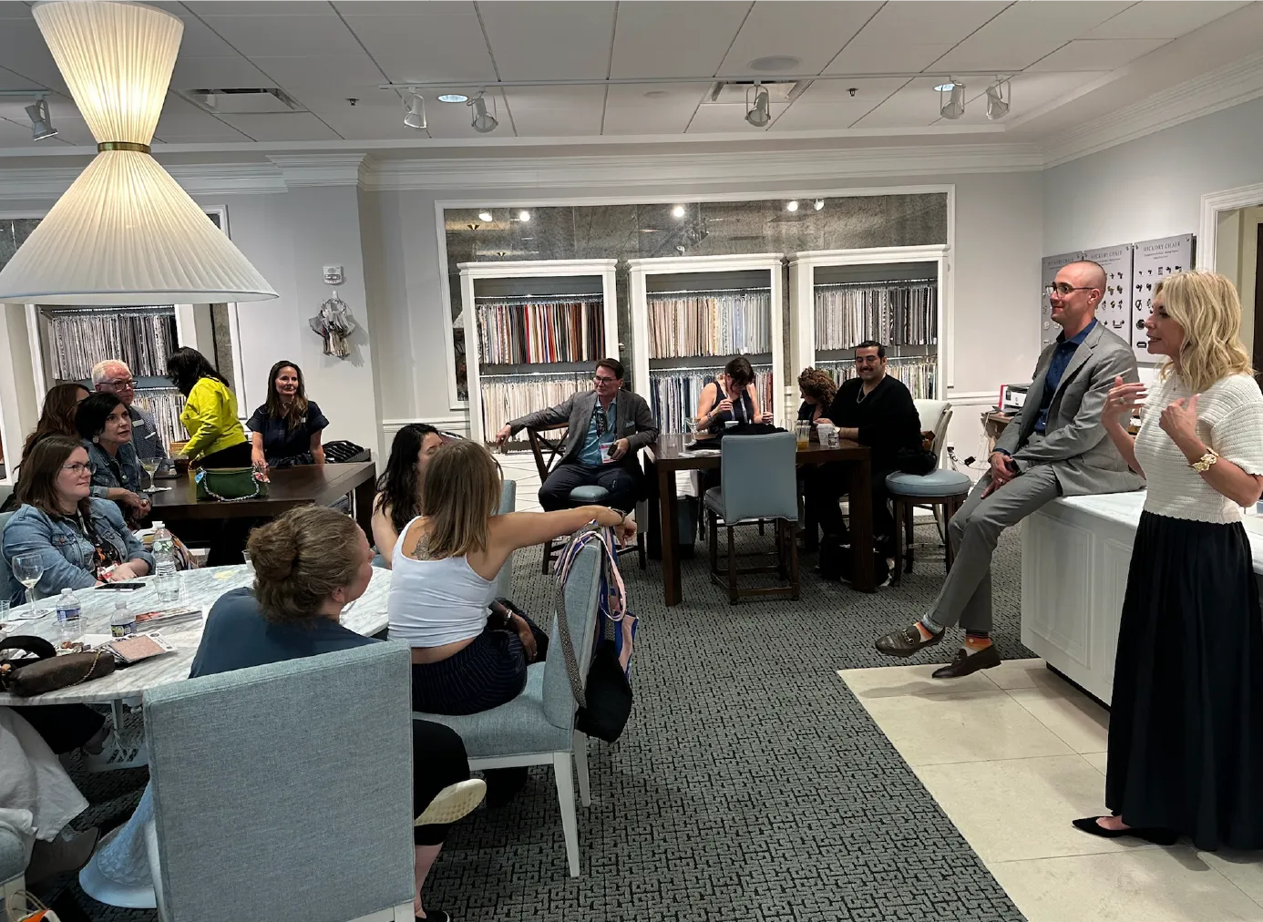 Traci Connell speaking to a group of interior designers gathered in a fabric showroom.