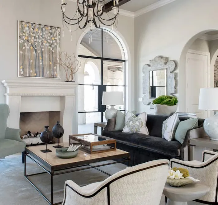 bright living room featuring a stone fireplace, elegant seating, and large arched windows.