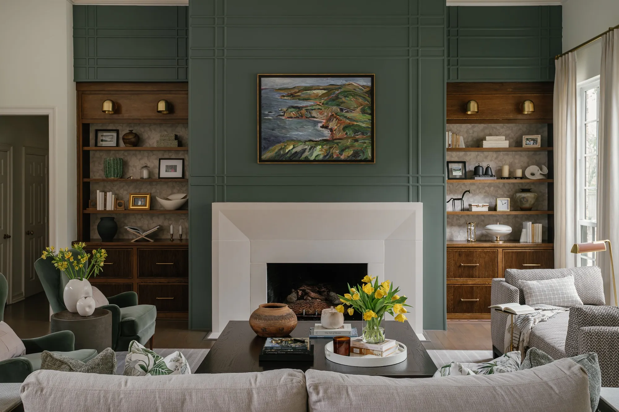 Dining nook with green panelled walls, a large framed abstract painting and blush upholstered chairs around a marble pedestal table.